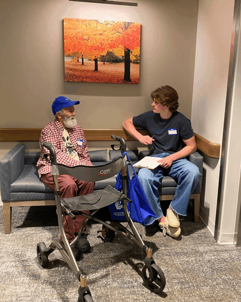 Older man and youth sitting on a chair. A walking aide also in photo.